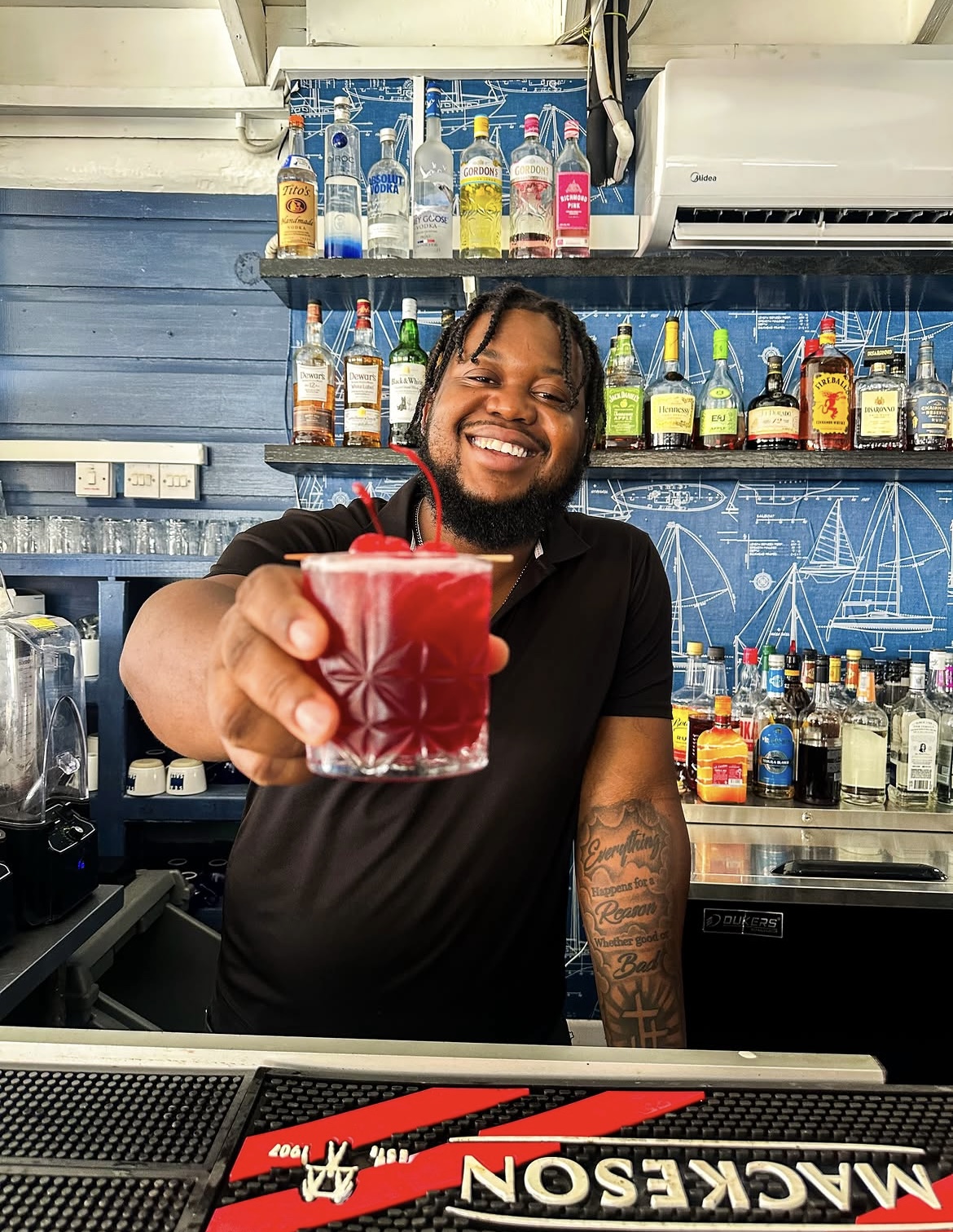 Sea Salt bartender smiling as he hands over a red rum cocktail
