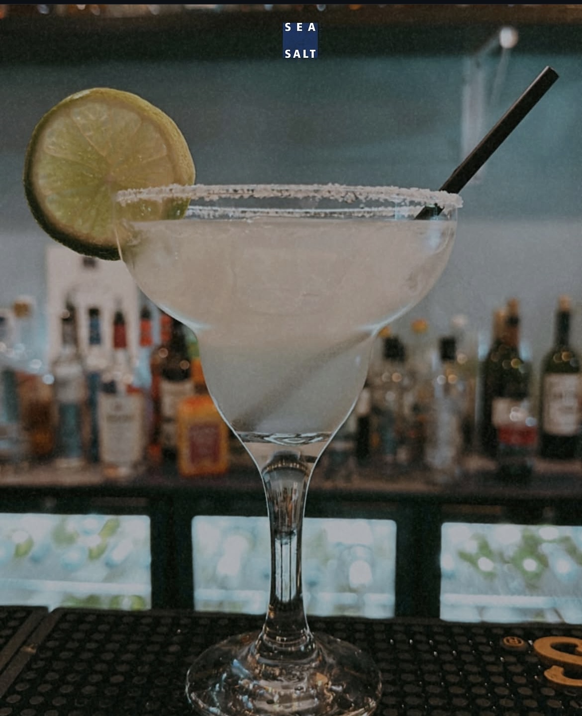 Salt-rimmed margarita with a lime wheel at the bar
