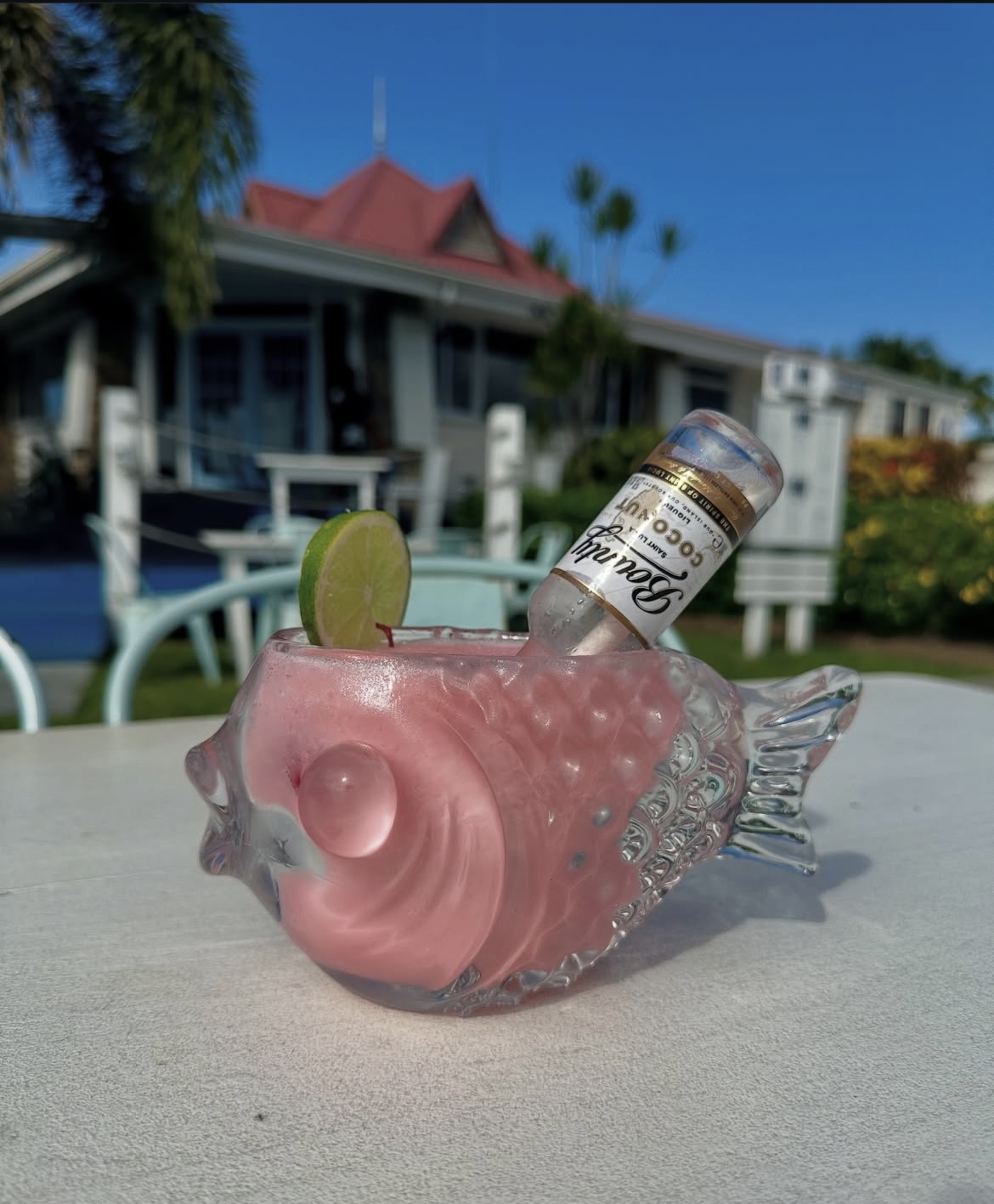 Pink rum cocktail served in a fish-shaped glass with Bounty coconut